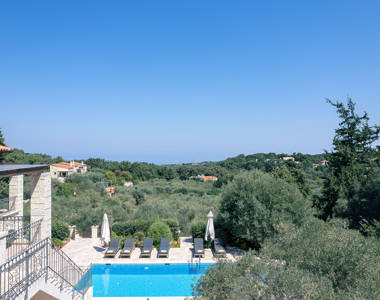 Vederi Estate Villa Melpomeni view of the villa pool and the rest of the villas in the mountain in the background
