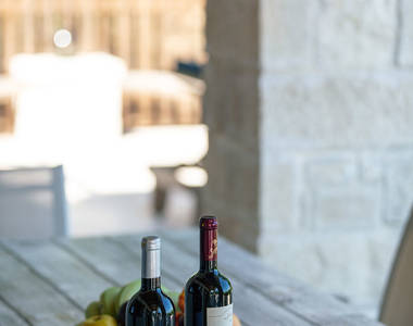 Vederi Estate Villa Melpomeni outdoor table with two bottles of wine, wine glasses and fruits