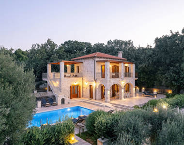 Vederi Estate Villa Melpomeni lit up exterior view of the villa at dusk