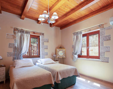 Vederi Estate Villa Melpomeni bedroom with two single beds, a bedside table, decorations and amenities