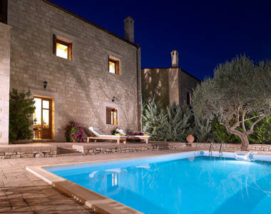 Vederi Estate Villa Kyveli private pool, sunbeds and villa exterior lit up at dusk