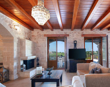 Vederi Estate Villa Melpomeni living room with fireplace, balcony view and amenities