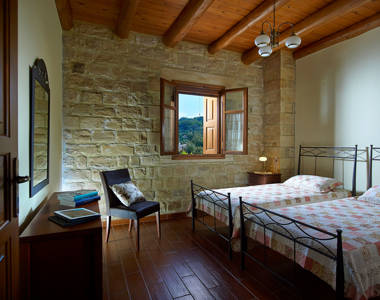 Vederi Estate Villa Kalypso bedroom with two single beds, a chair, a bedside table and amenities